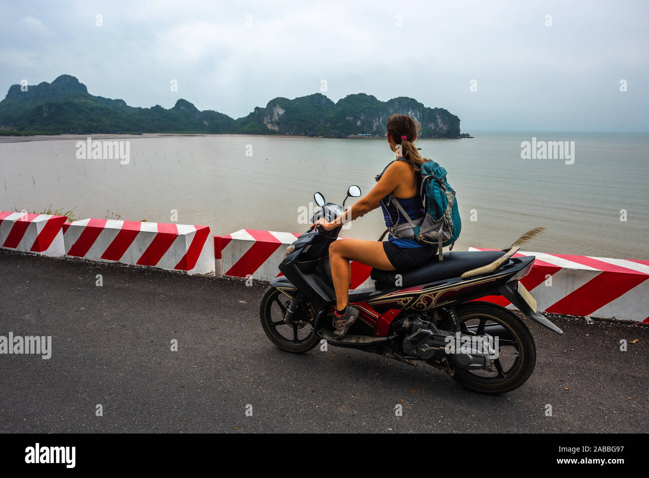 Cat Ba Island Vietnam touristische Mädchen auf einem Roller tragen Rucksack bewundert einen schönen Blick auf Ha Long Bay Stockfoto