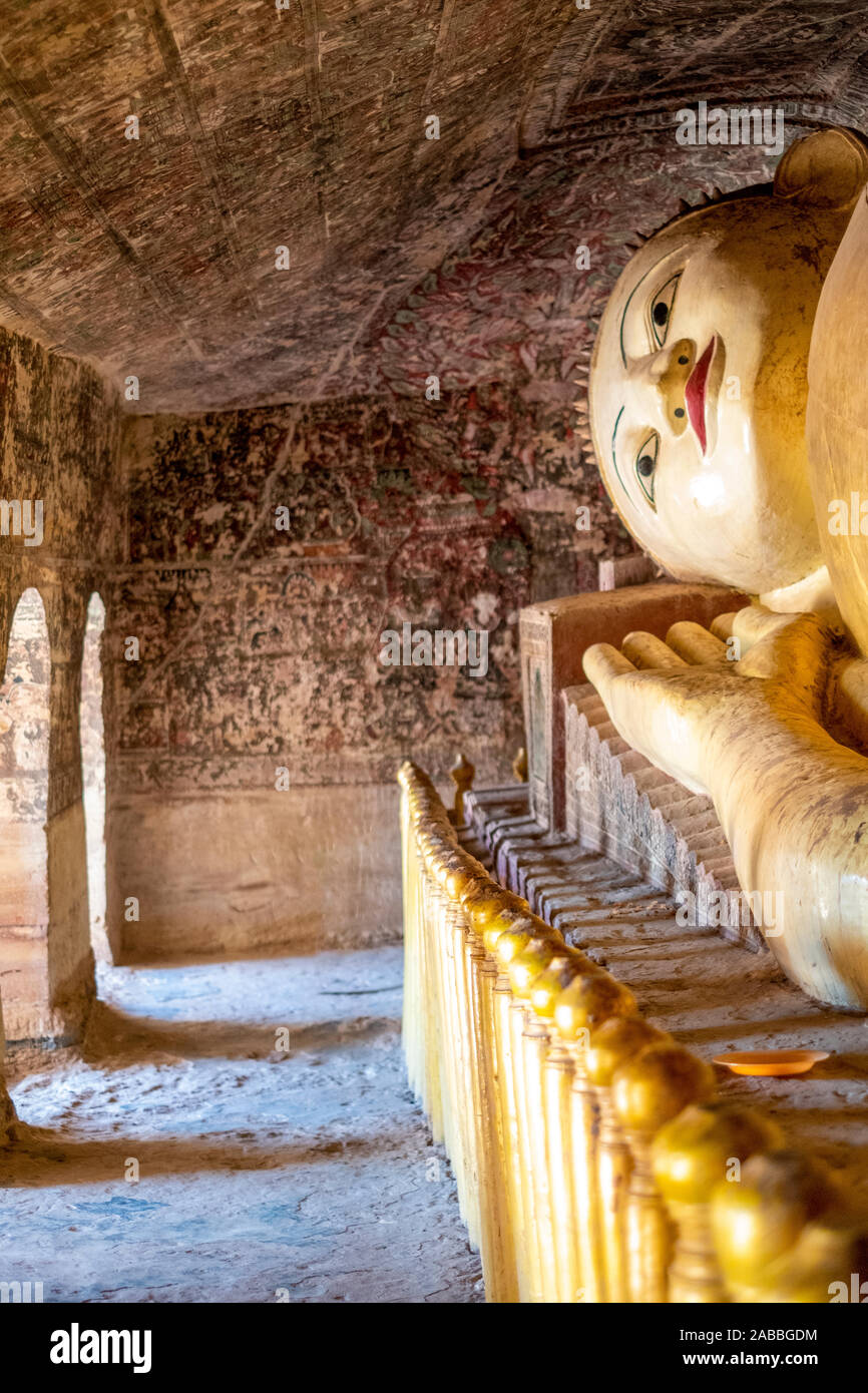 Eine liegende Buddha Skulptur gefunden im Phowin Taung Höhlen in der Nähe des Chindwin Fluss, Myanmar (Birma) mit kunstvollen Wandmalereien um Sie herum Stockfoto