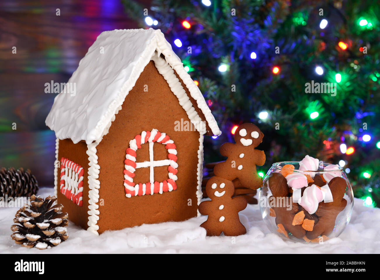 Die von Hand essbare Lebkuchenhaus, kleine Männer und Süßigkeit, Tannenbaum mit Kranz im Hintergrund Stockfoto