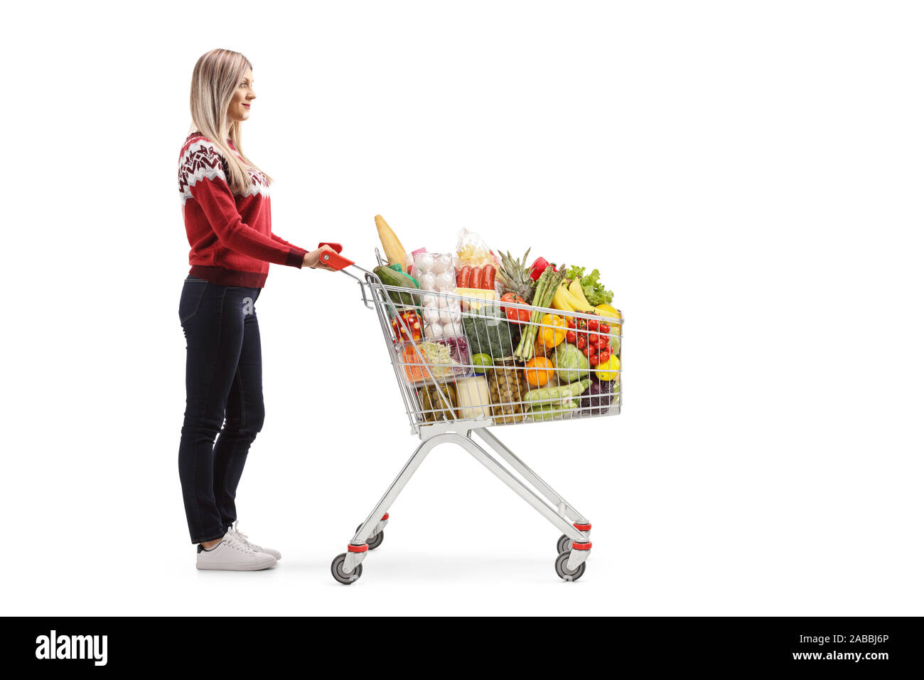 Volle Länge Profil Schoß einer Frau, die mit der Nahrung in einem Warenkorb auf weißem Hintergrund Stockfoto
