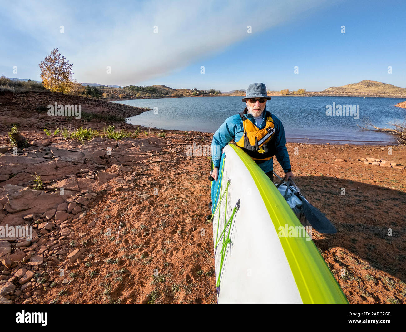 Ältere männliche Paddler mit Stand up paddleboard auf einem See in COlorado Ausläufern, POV von Action Kamera im Herbst Landschaft Stockfoto