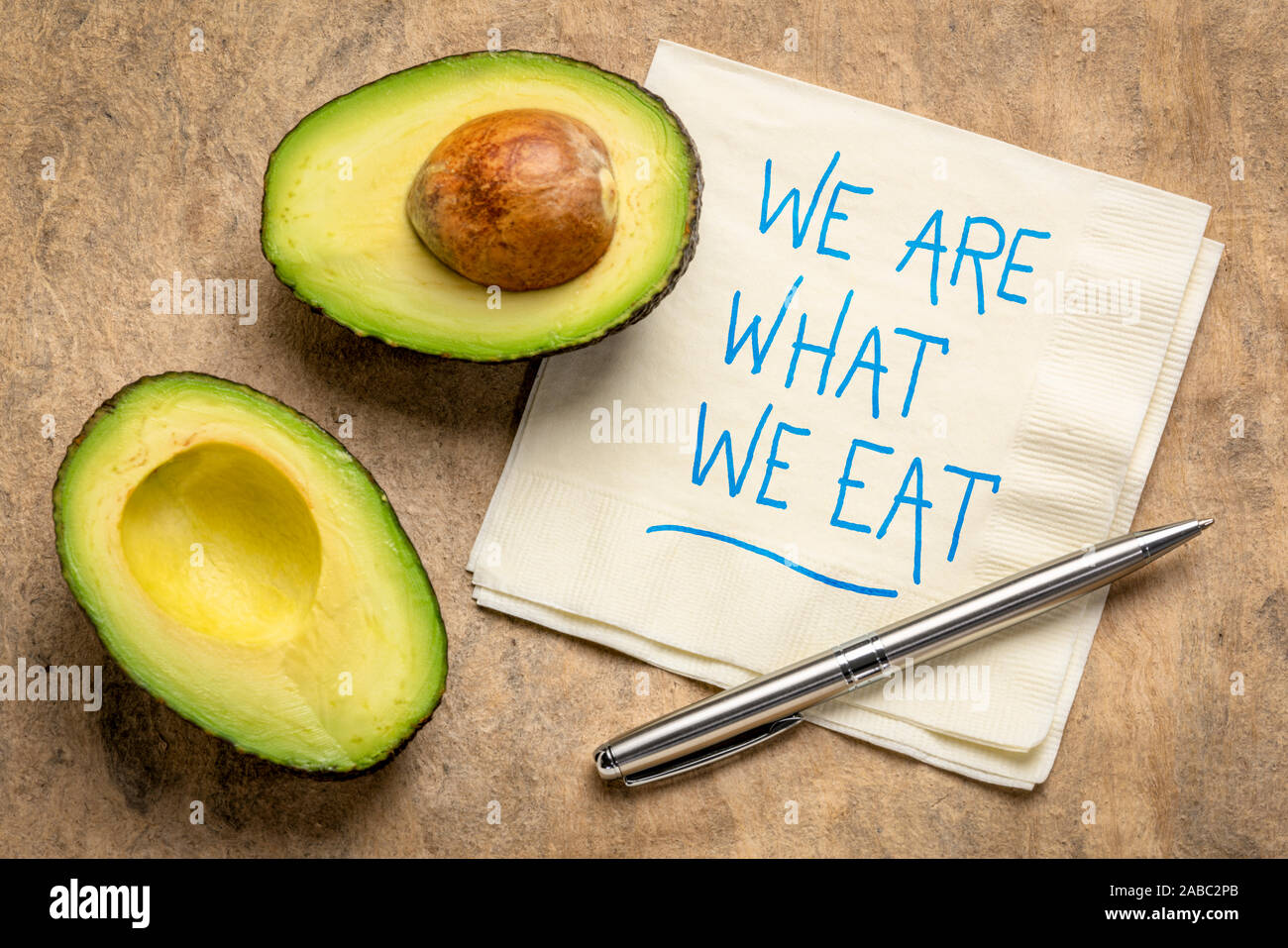 Wir sind, was wir essen. Handschrift auf eine Serviette mit einem Schnitt Avocado - gesunde Lebensweise und Ernährung Konzept. Stockfoto