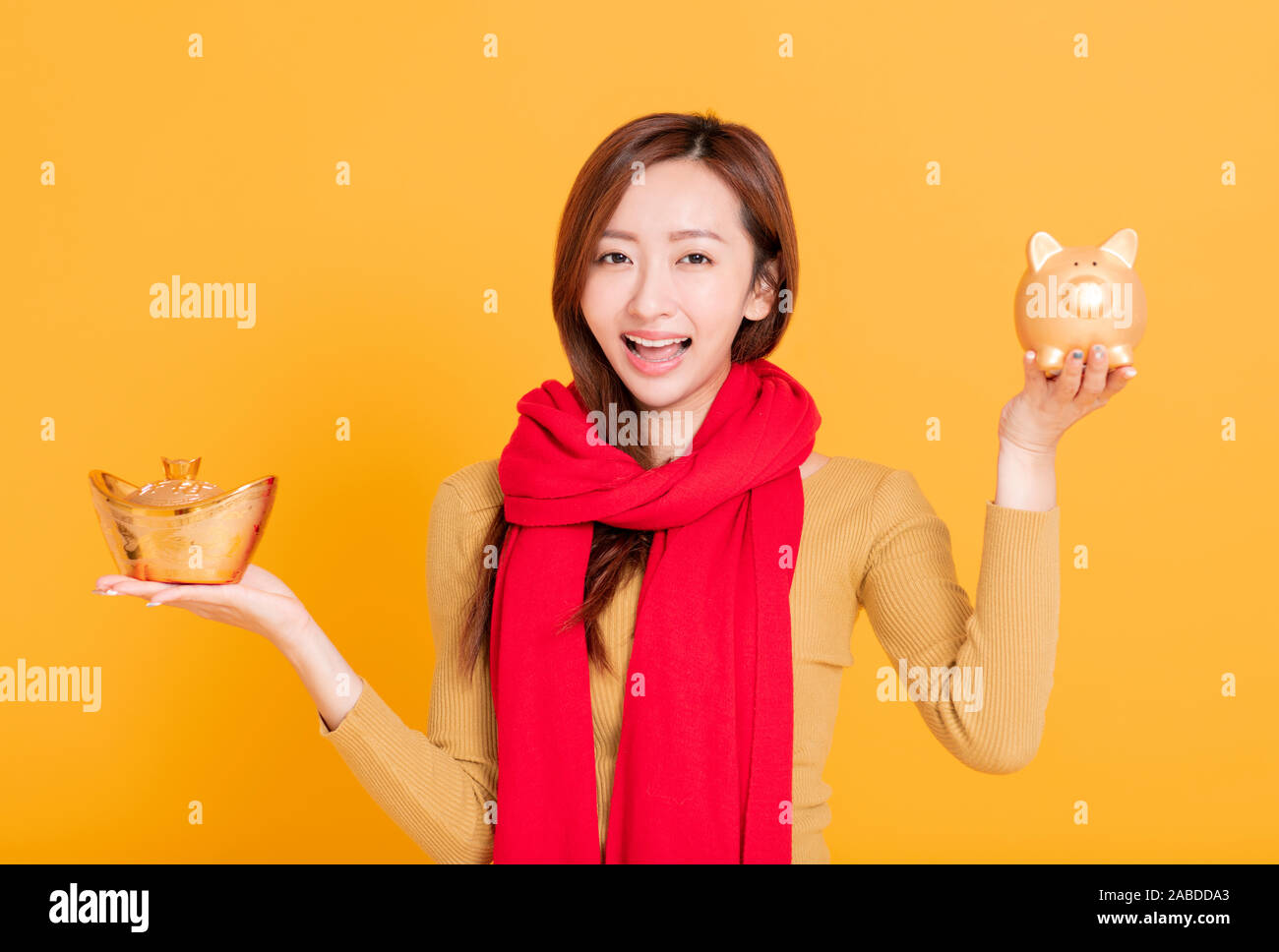 Schöne asiatische junge Frau, chinesische Goldbarren und Sparschwein. chinesischen Text: reich und glücklich Stockfoto