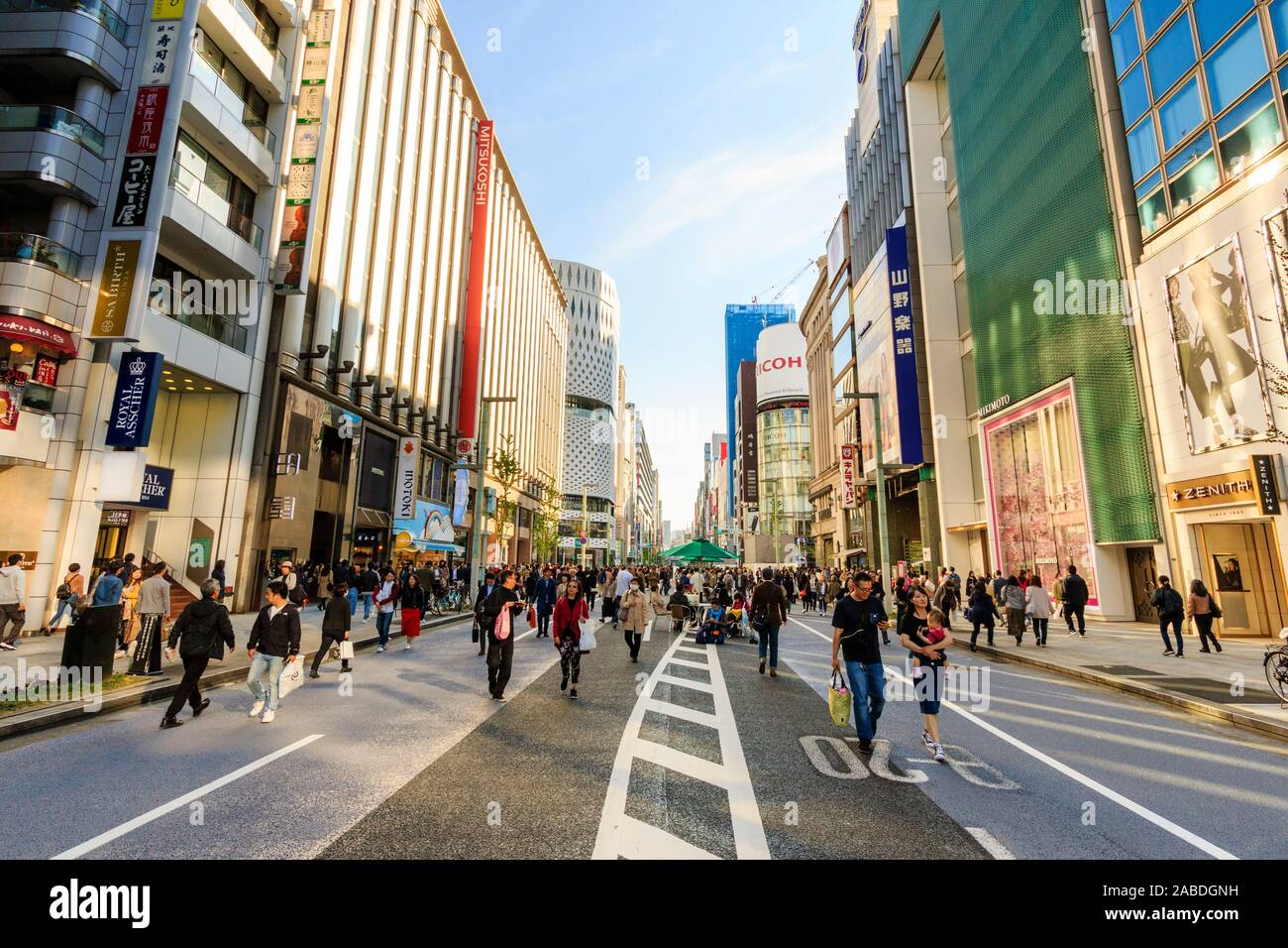 Blick auf die Straße entlang der Einkaufsstraße Ginza von Mikimoto und Mitsukoshi Läden an einem langen Wochenende, als es eine Fußgängerzone ist. Goldene Stunde. Stockfoto