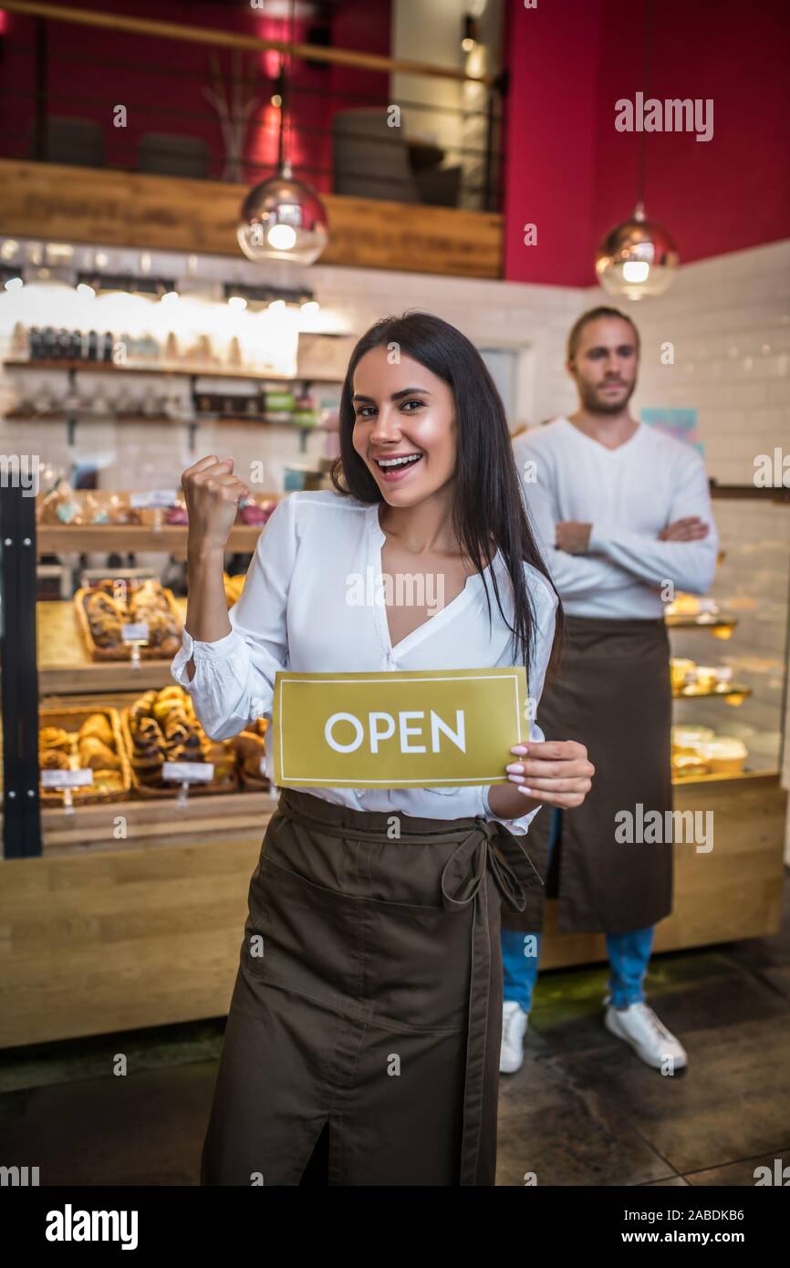Frau mit Schürze Eröffnung Bäckerei mit ihrem erfolgreichen Mann Stockfoto