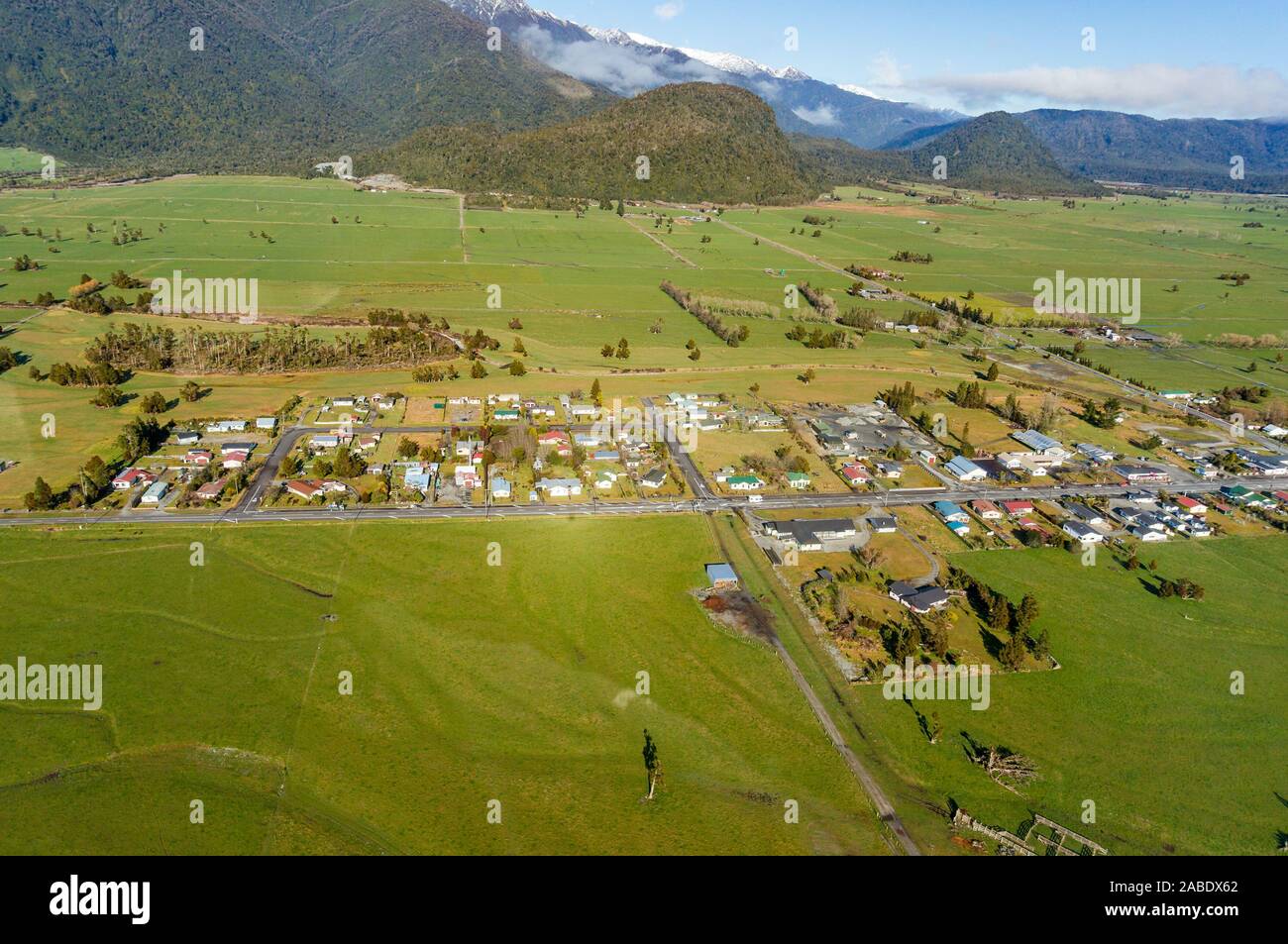 Luftaufnahme von kleinen Neuseeland Dorf, Stadt von grünen Feldern und Bauernhöfen umgeben. Whataroa, South Island. Neuseeland Stockfoto