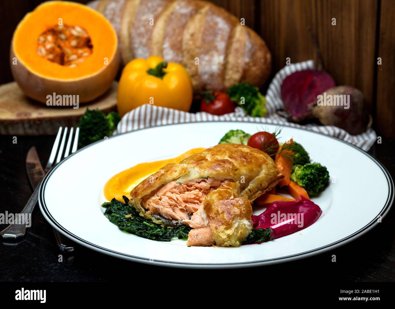 Lachs pie mit gerösteten Kräutern, Gemüse und saurer Sauce serviert. Stockfoto