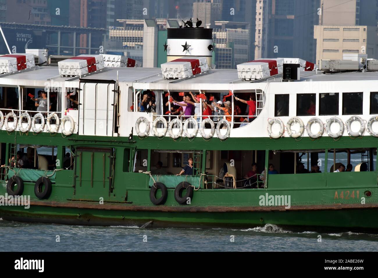 Menschen wave Flags auf einer Fähre zum 70. Jahrestag der VR China in Hongkong, China, 1. Oktober 2019 zu feiern. Stockfoto