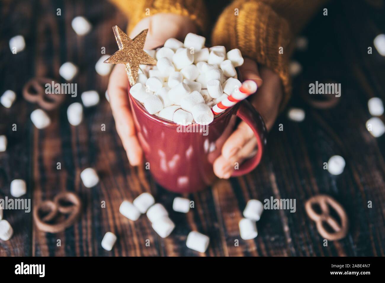Frau in Gelb pullover Holding heiße Schokolade Tasse mit Marshmallow auf dunklen Hintergrund. Stockfoto