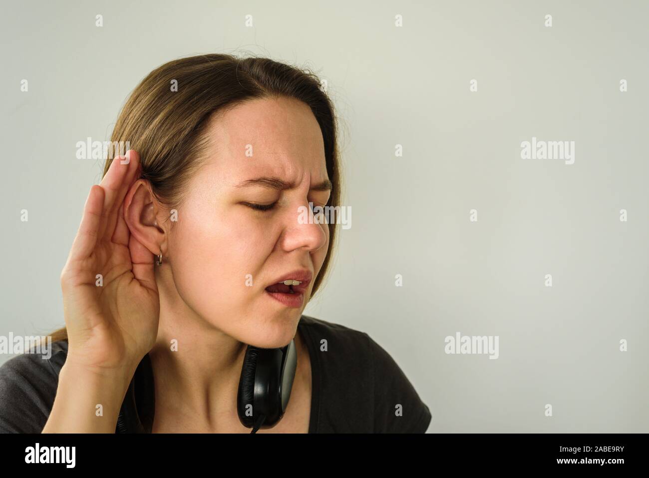 Junge Frau mit Anhörung Geste. Hörbehinderte Menschen Probleme. Ear Tag Stockfoto