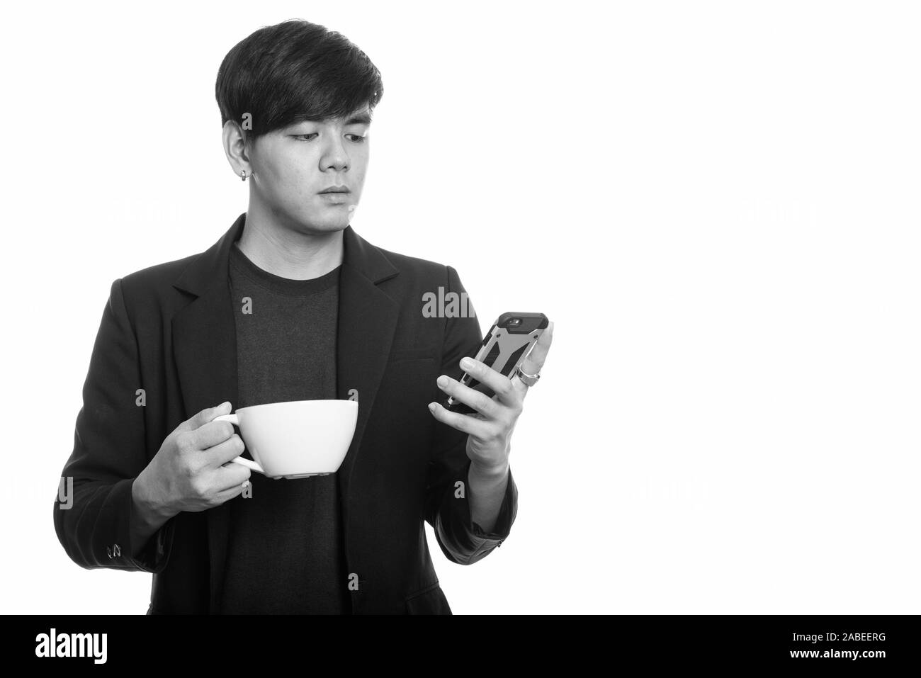 Studio shot cool aussehenden Asiatische Geschäftsmann mit Mobiltelefon, während Sie Kaffee Tasse Stockfoto