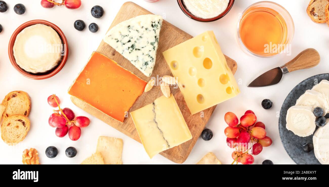 Eine Auswahl an Käse Panorama, geschossen von oben auf einem weißen Hintergrund. Blue Käse, Quark und andere Arten mit Obst und Nüssen, Wein und Trauben Stockfoto