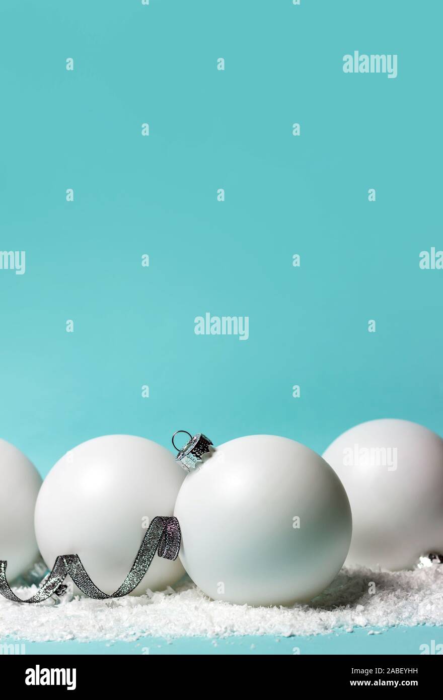 Weiße Weihnachten Kugeln, Sterne, glänzendes Silber Farbband und Schnee auf hellblauem Hintergrund. Kopieren Sie Platz. Stockfoto
