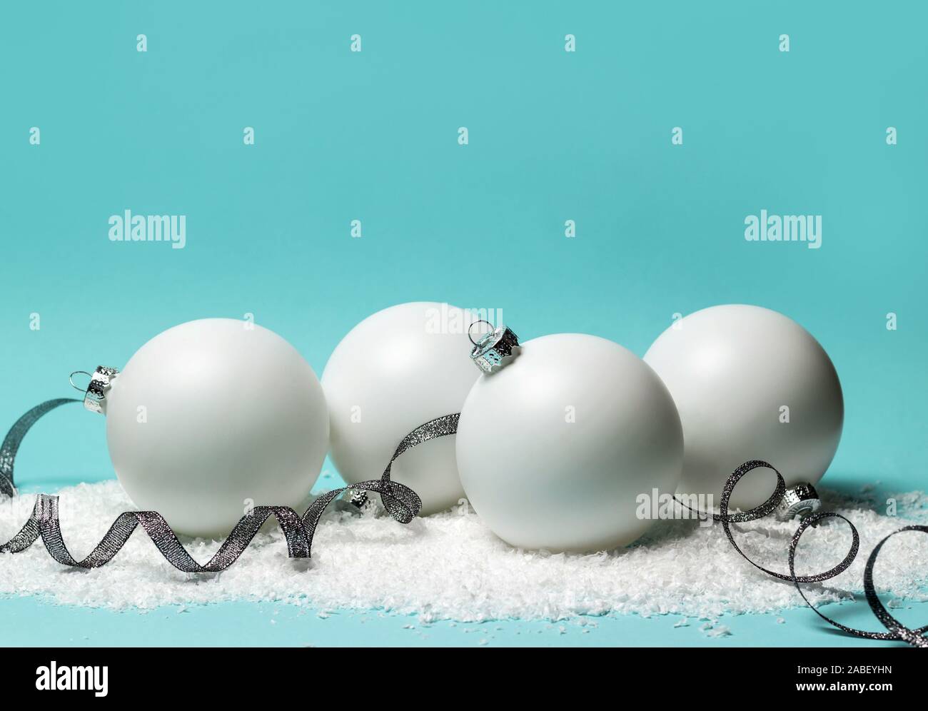 Weiße Weihnachten Kugeln, Sterne, glänzendes Silber Farbband und Schnee auf hellblauem Hintergrund. Kopieren Sie Platz. Stockfoto