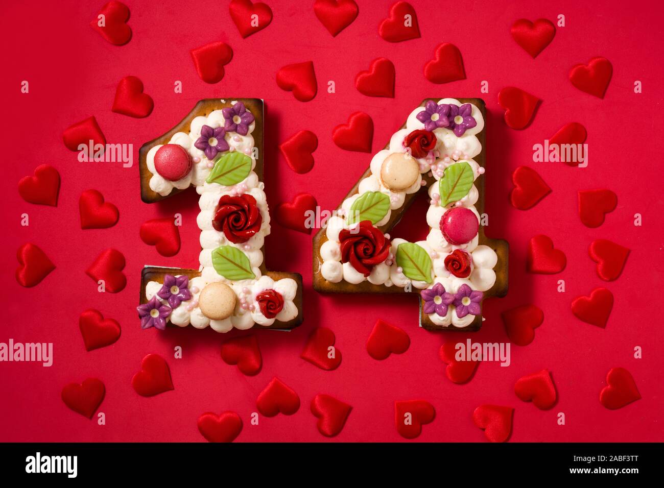 Valentinstag Kuchen mit 14 Form Anzahl und Herzen auf rotem Hintergrund Stockfoto