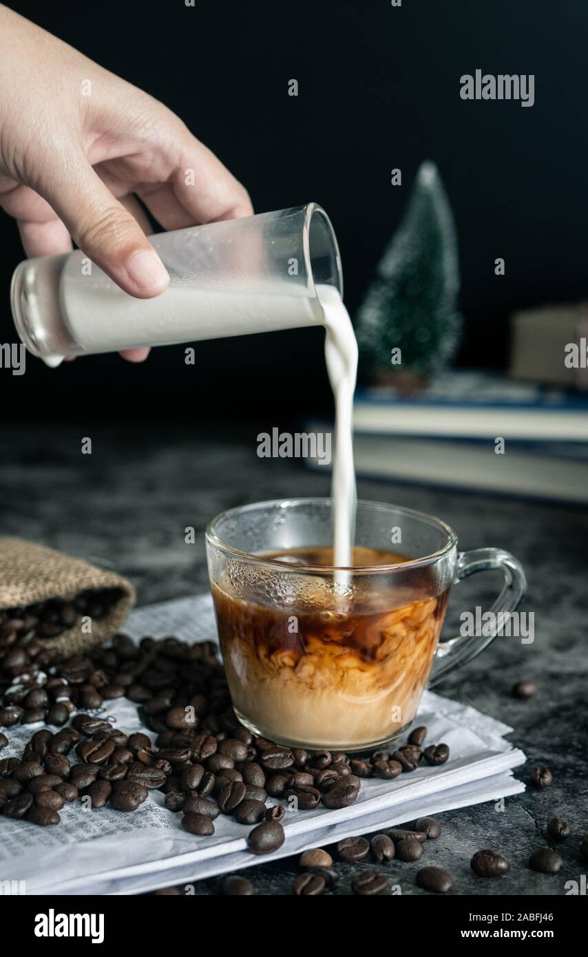 Barista latte. Hand gießen Milch in eine Tasse Espresso, Kaffee trinken. vertikale Bild 7/8 Shot Stockfoto