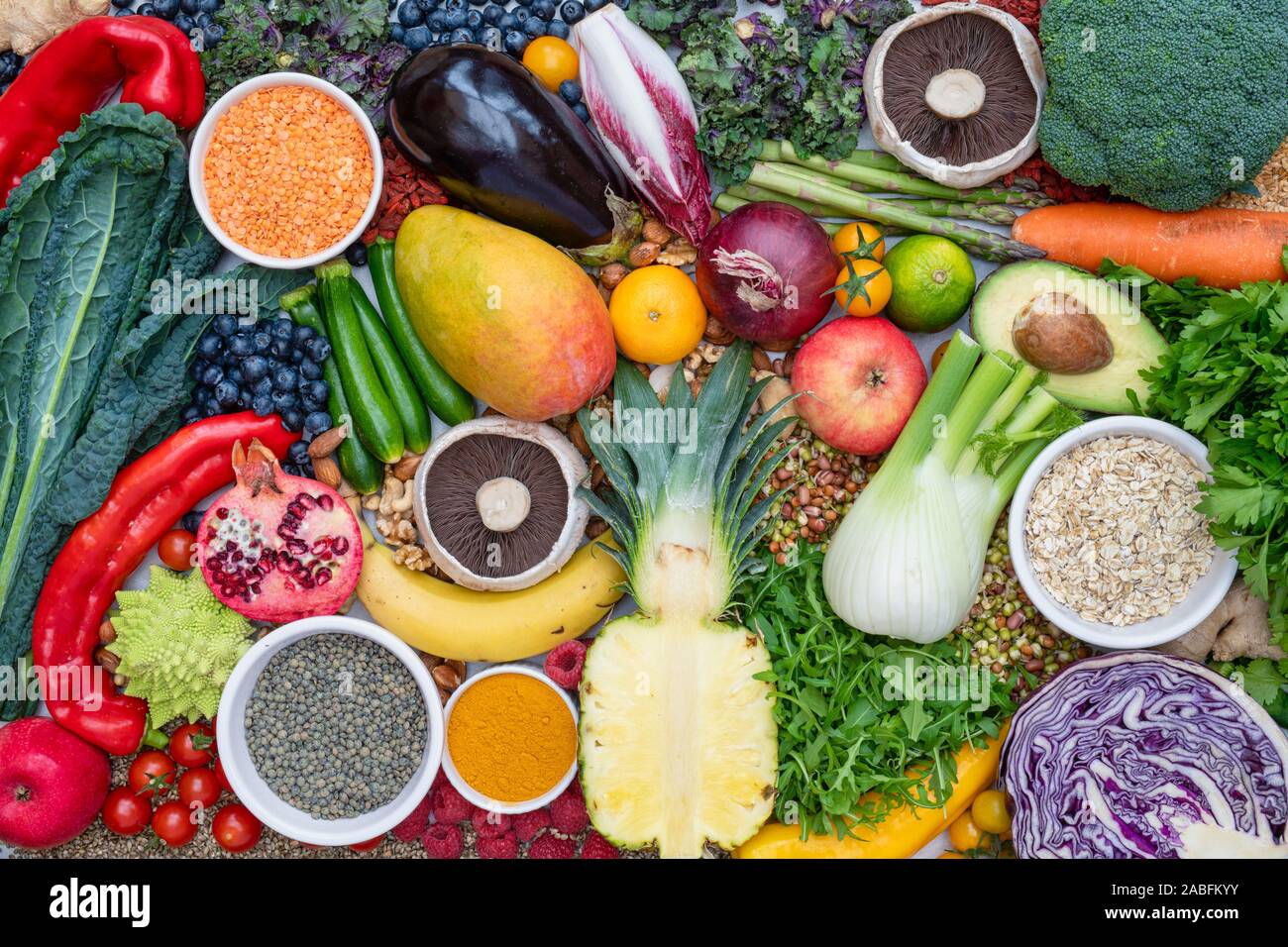 Vegan. Obst Gemüse linsen Gewürze Kräuter Nüsse und Samen auf weißem Schiefer Hintergrund Stockfoto