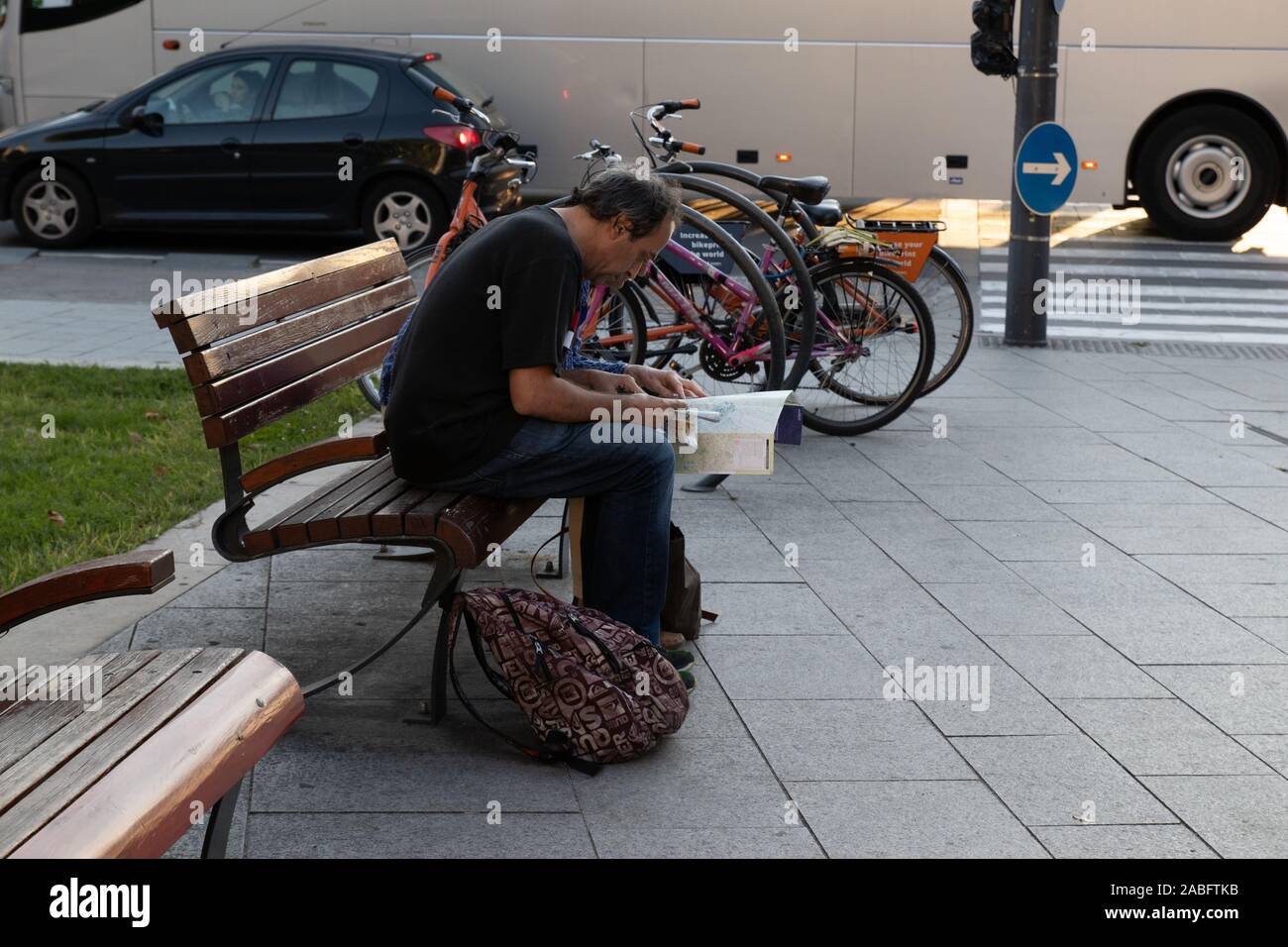 Ein Tourist sitzt auf einer Bank und sucht nach einem Ort auf der Karte. Stockfoto