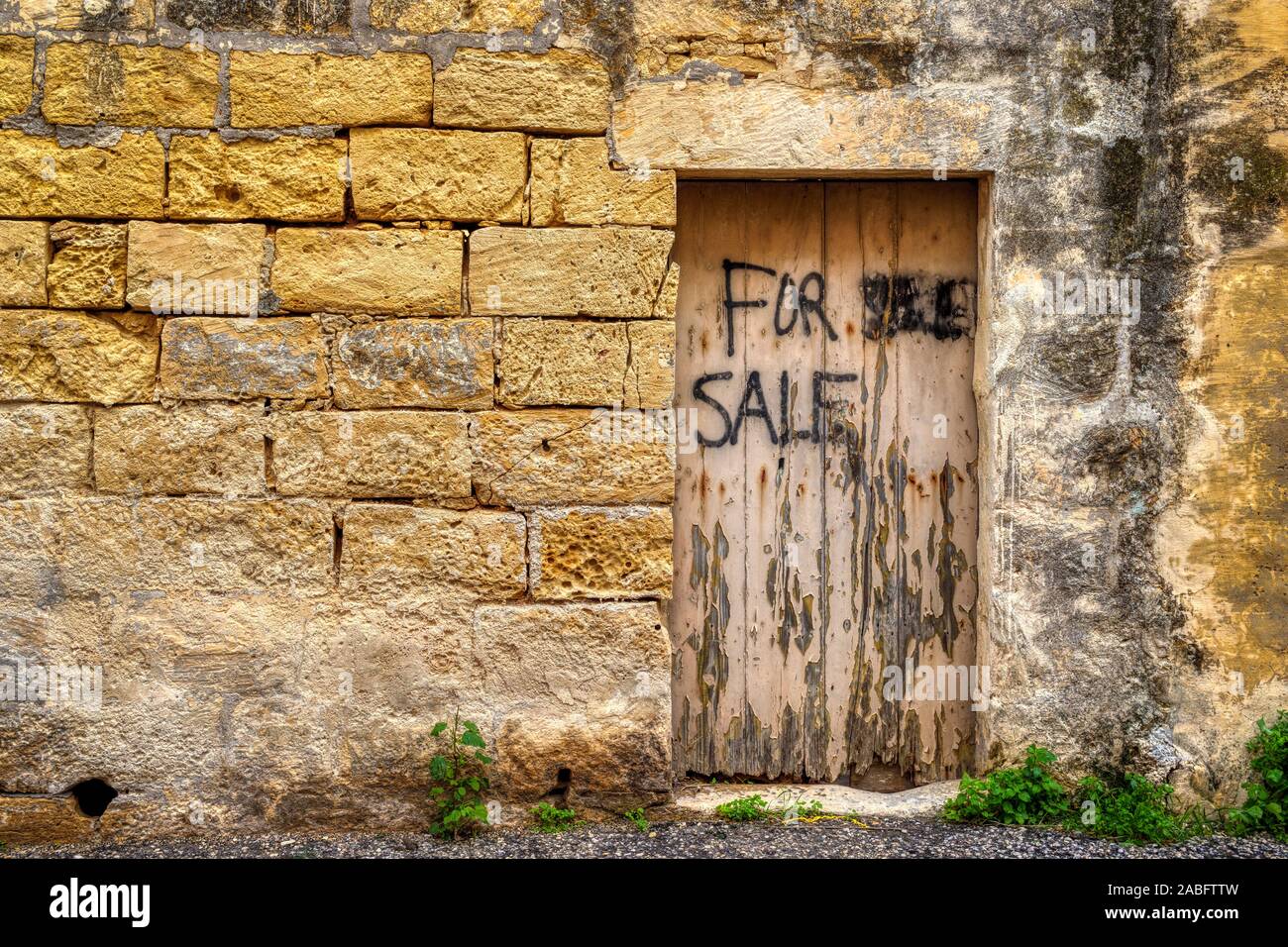 Traditionelle verwitterte und gealterte Kalkstein block Wand mit hölzernen Tür. Teil eines Gebäudes auf der Mittelmeerinsel Gozo, Malta. Stockfoto