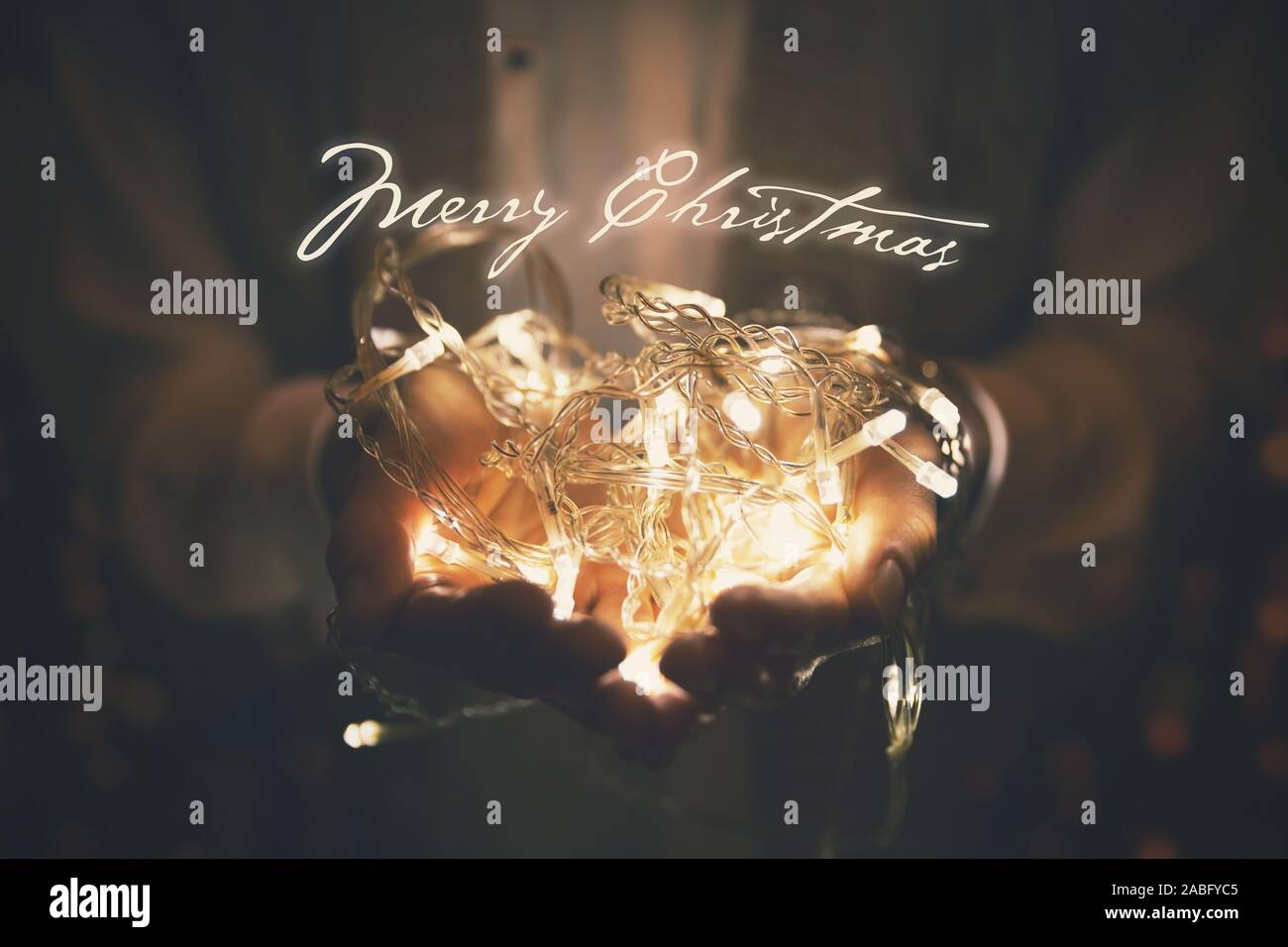 Frohe Weihnachten Grußkarte - led Girlande in Frau Hände glühen Stockfoto