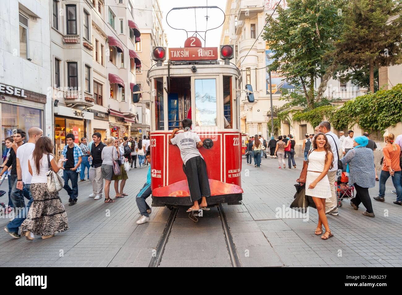 Kind, das eine Fahrt auf der Rückseite einer alten roten Straßenbahn auf Istiklal Caddesi, Istanbul, Türkei anzieht Stockfoto