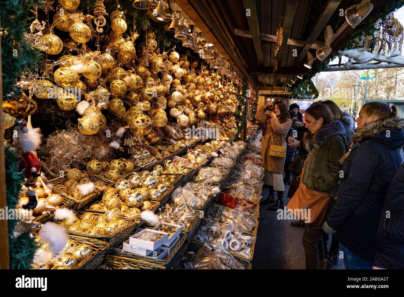 Wien, Österreich - 11.23.2019: junge Frauen Touristen bewundern hängenden golden Christmas ornament Dekoration Kiosk stehen auf einem winter Markt Rathausplatz Stockfoto