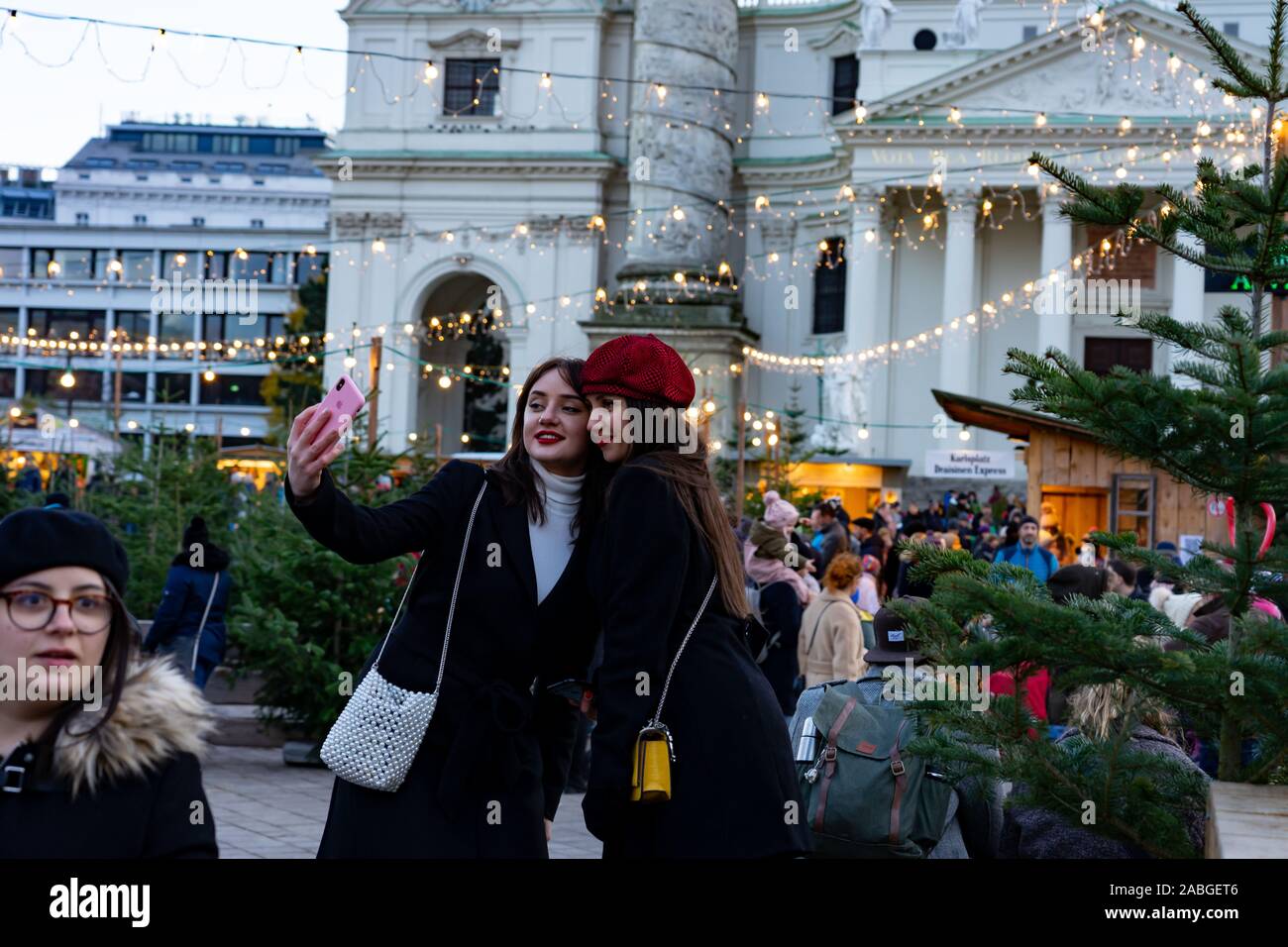 Wien, Österreich - 11.23.2019: 2 junge Frauen Touristen unter selfie in der Weihnachtsmarkt am Karlsplatz. Stockfoto