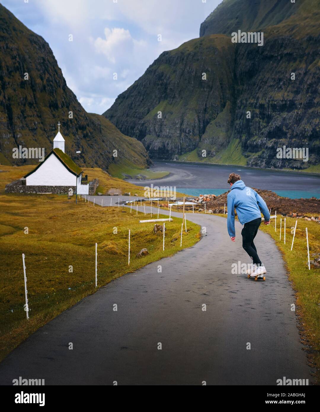 Jungen Skater, der auf einem Skateboard durch die wunderschöne Landschaft der Färöer Inseln Stockfoto