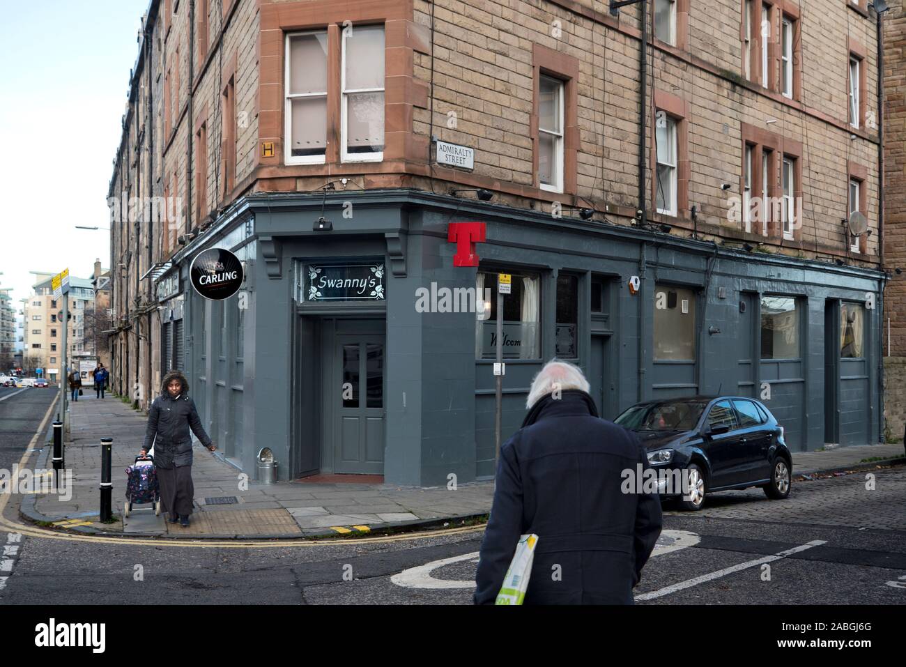 Fußgänger, die an der Swanny's Bar in der North Junction Street in Leith, Edinburgh, Schottland, Großbritannien, vorbei gehen. Stockfoto