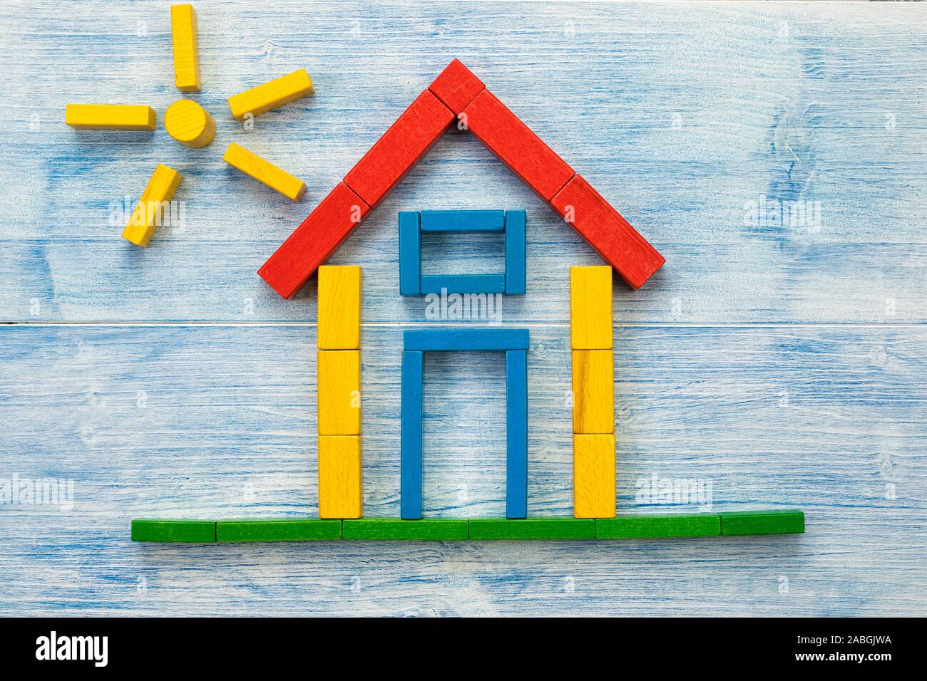 Haus und Sonne aus Bausteinen auf Blau Holz Hintergrund flach Stockfoto