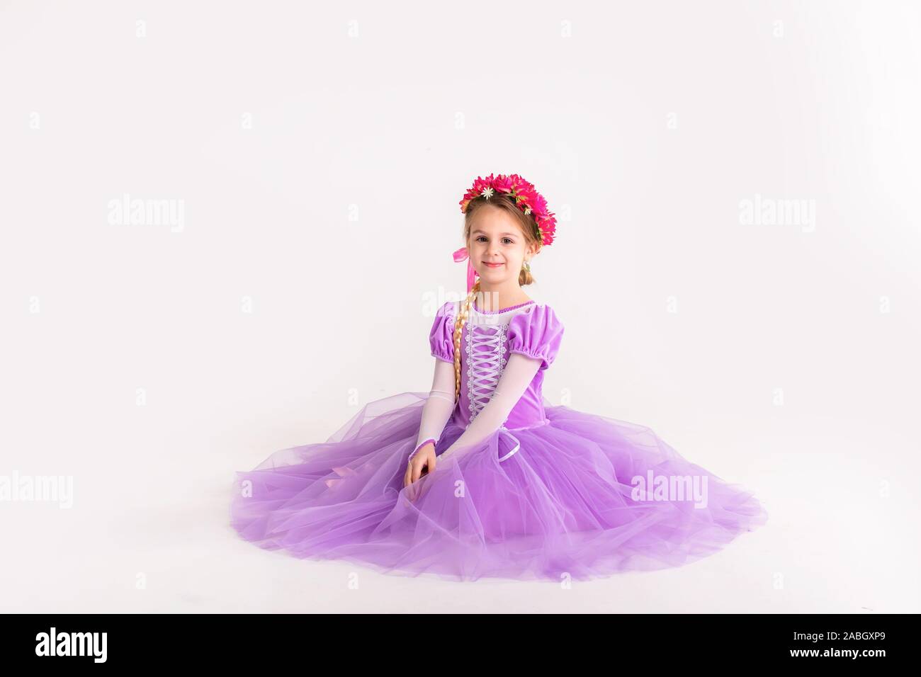 Kleine blonde Mädchen mit lila Fairy Princess Dress auf weißem Hintergrund. Kinder Kostüm für das neue Jahr. Stockfoto
