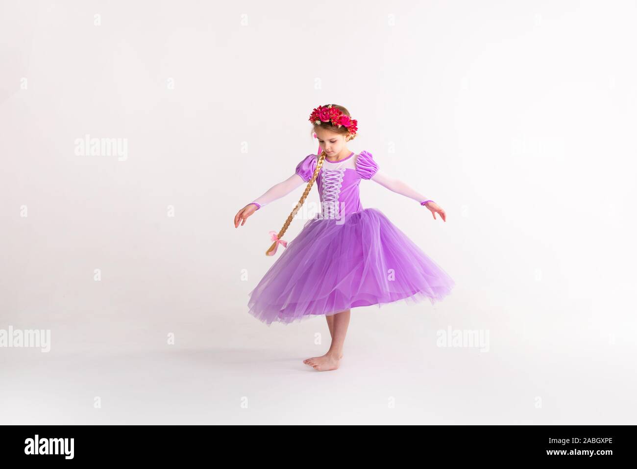 Kleine blonde Mädchen mit lila Fairy Princess Dress auf weißem Hintergrund. Kinder Kostüm für das neue Jahr. Stockfoto