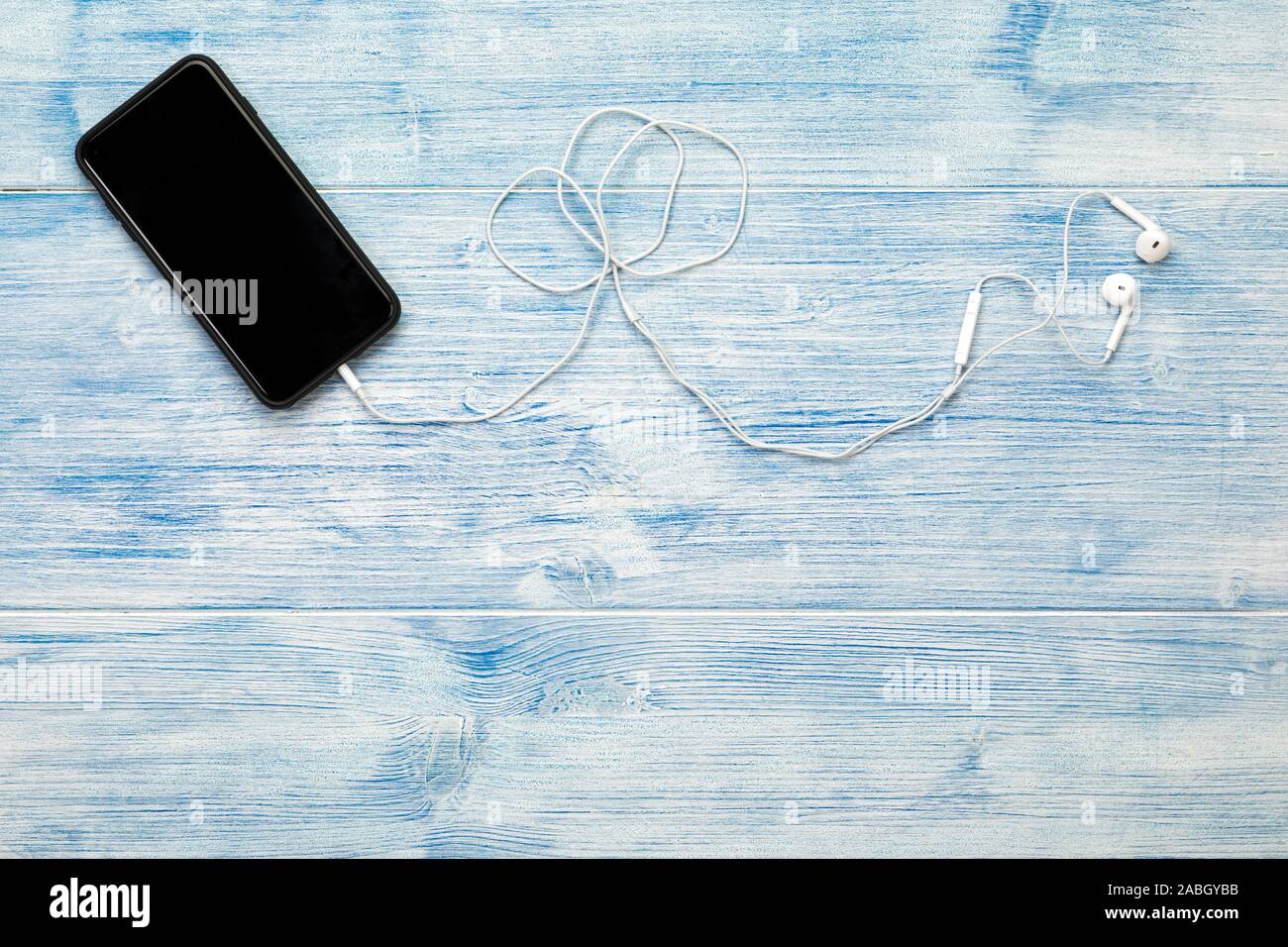 Smart Phone mit Kopfhörern auf Blau Holz- Hintergrund Stockfoto