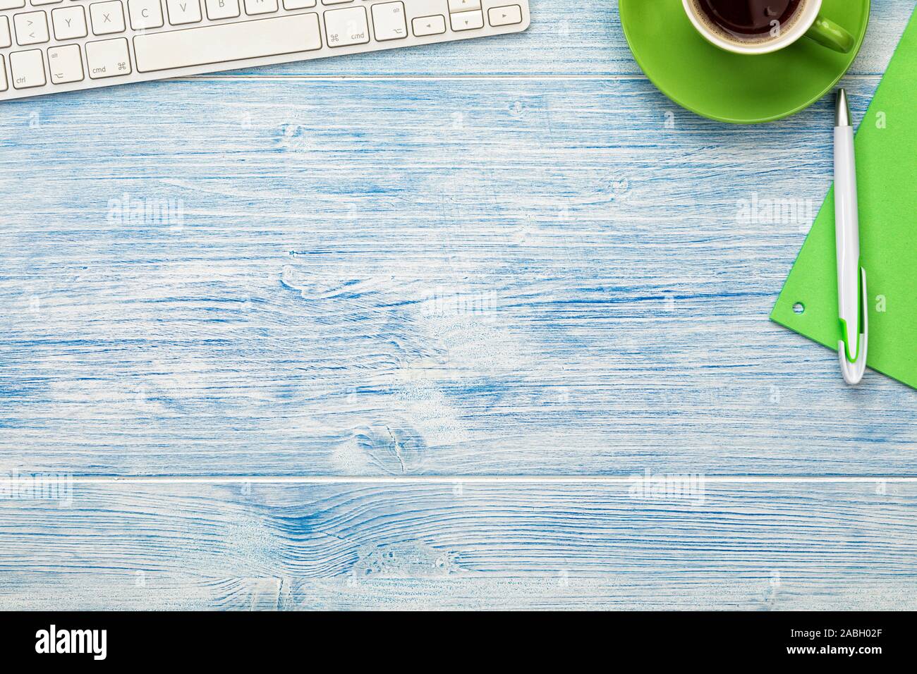 Hintergrund mit Computer Tastatur, Kaffee Tasse und Besteck auf Blau Holz- Desktop angeordnet. Große Kopie Raum. Stockfoto