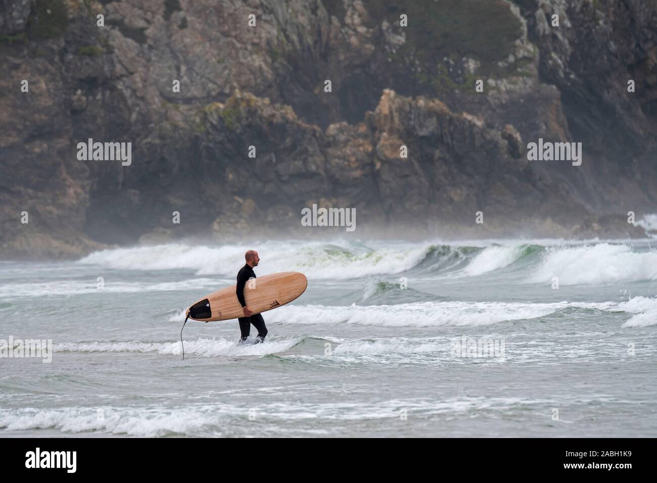 Surfer mit Surfbrett am Strand zu Fuß in das Wasser in der Nähe von Sea Cliff an der Pointe du Raz, Finistère, Bretagne, Frankreich Stockfoto