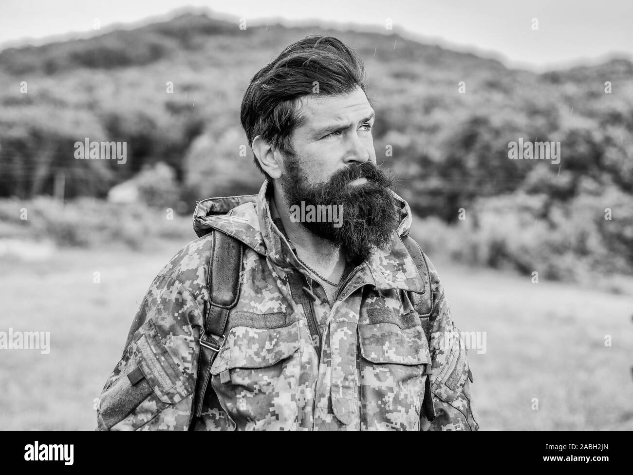 Brutale manly Kerl. Wandern und Reisen. Wochenende Freizeit und Urlaub. Wanderer bärtiger Mann Wandern. Wanderer bereit für Abenteuer. Man bärtige Backpacker Verschleiß camouflage Jacke Natur Hintergrund. Wanderer tourist. Stockfoto