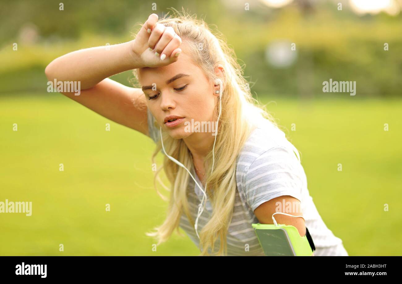 Müde Läuferin im Park eine Pause - Sportliche Frau atmen und Ausruhen nach Outdoor Sport Stockfoto