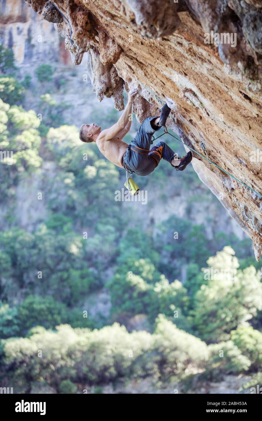 Junge männliche Kletterer suchen, um sich über anspruchsvolle Strecke auf überhängenden Klippe Stockfoto