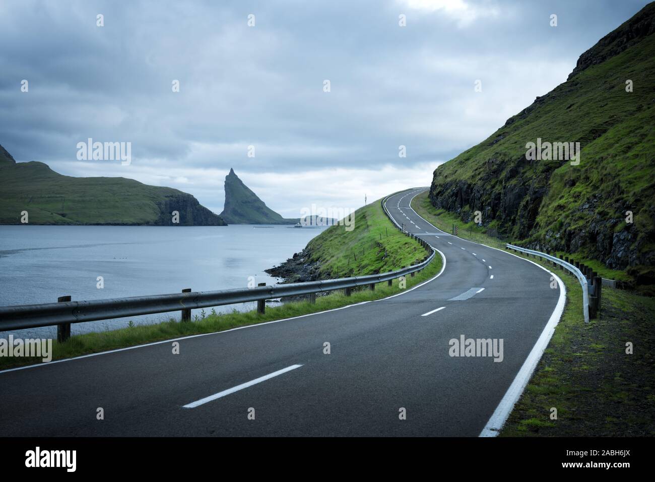 Dramatische Abendlicher Blick von der Straße und der Drangarnir und Tindholmur Felsen im Hintergrund auf der Insel Vagar, Färöer, Dänemark Stockfoto