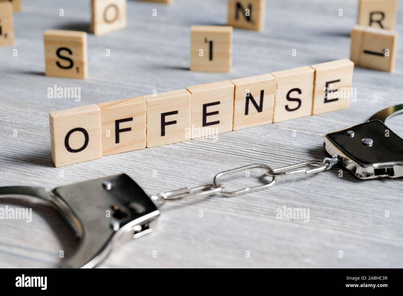 Ein Wort aus Holz Buchstaben ist eine Straftat. Metall Handschellen auf grauem Hintergrund. Das Konzept der das Gesetz zu brechen. Close Up. Stockfoto