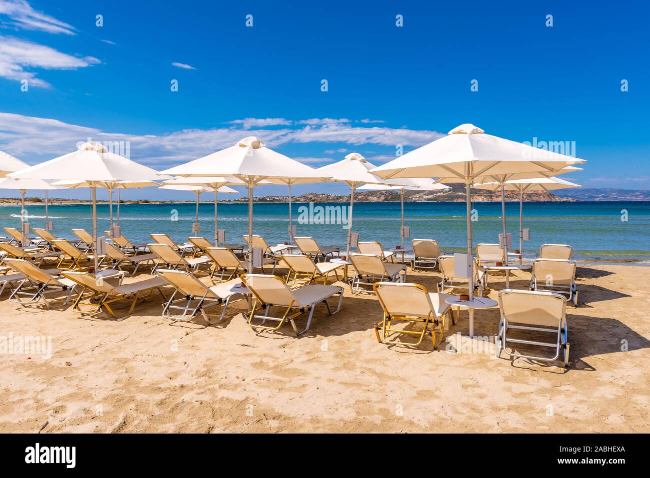 Sonnenschirme und Liegestühle am Strand von Agios Georgios, sehr beliebtes Resort mit feinem goldenen Sand und kristallklarem Wasser. Insel Naxos, Griechenland. V Stockfoto