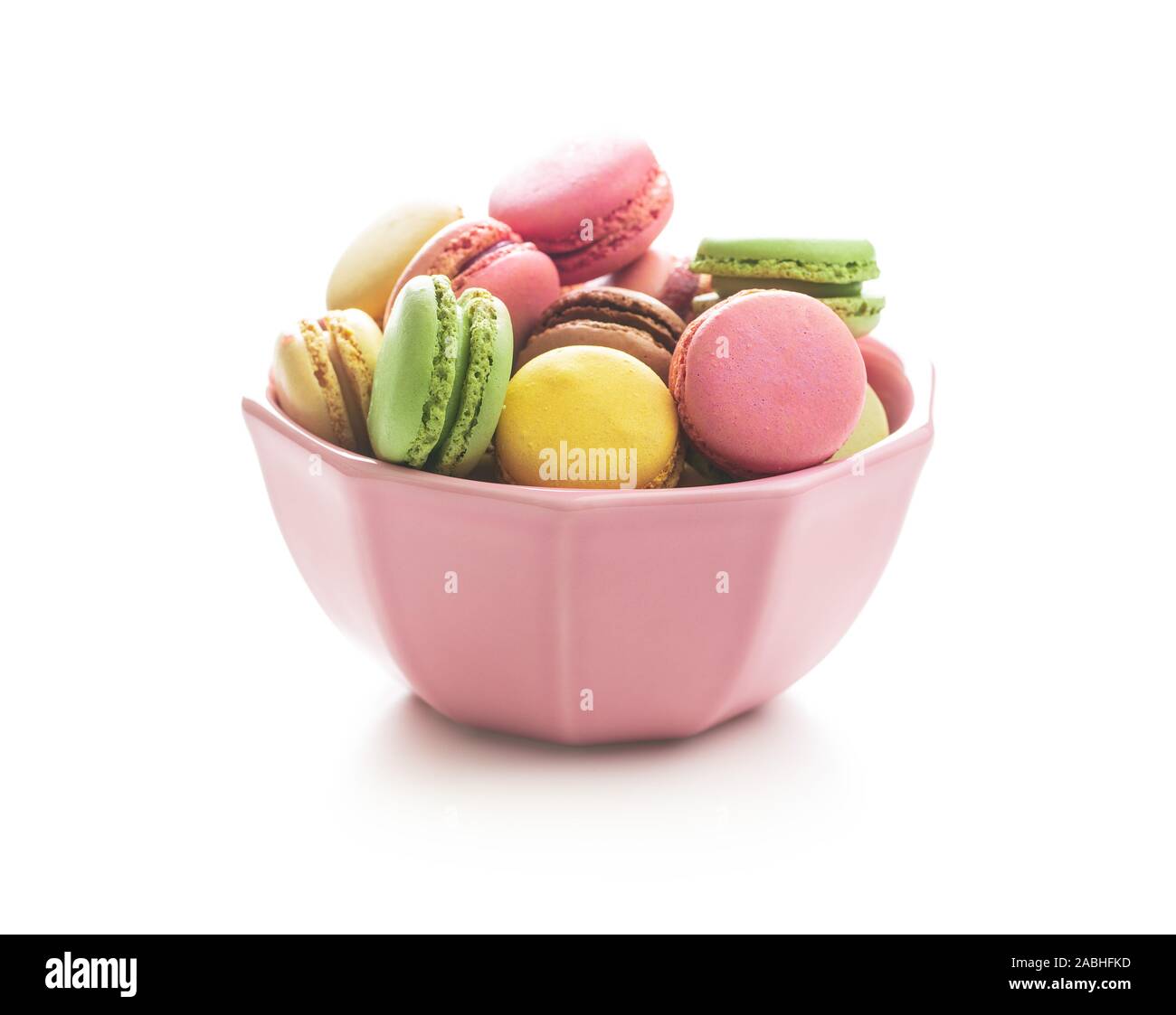 Süße bunte Macarons in Schüssel auf weißem Hintergrund. Stockfoto