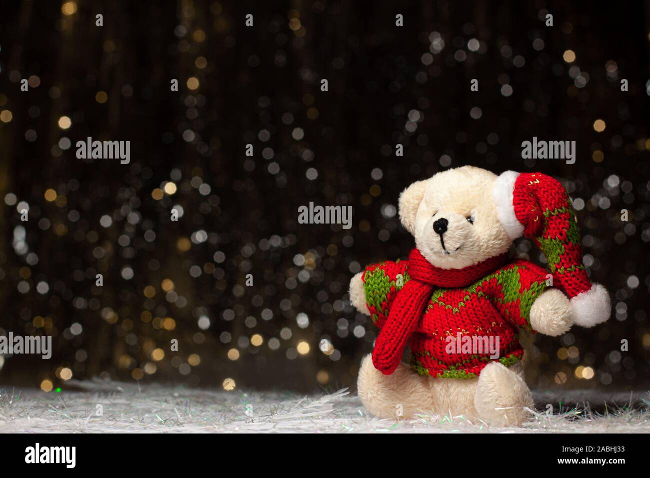 Weihnachten Ansicht der Teddybär in rot grünen Pullover und Mütze auf dunklem Hintergrund mit Silber und Gold. Urlaub Konzept mit Kopie Raum Stockfoto