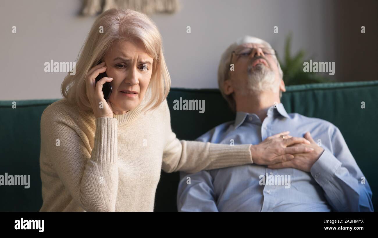 Frau macht Notruf, während Mann mit Herzinfarkt liegt Stockfoto
