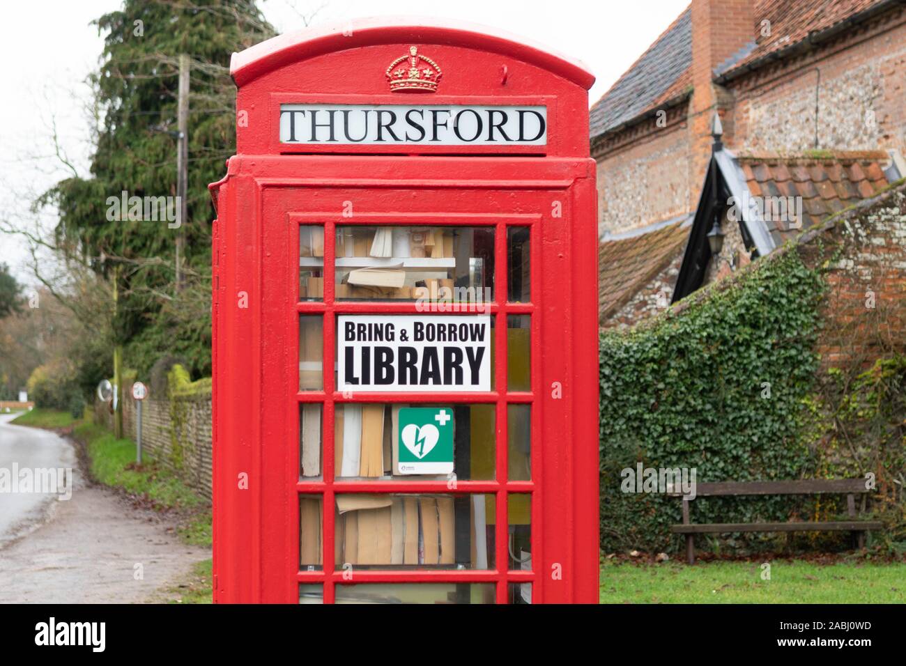 Rotes Telefon phone Box als lokale Bibliothek und Defibrillator, Thursford, Norfolk, England, Großbritannien Stockfoto