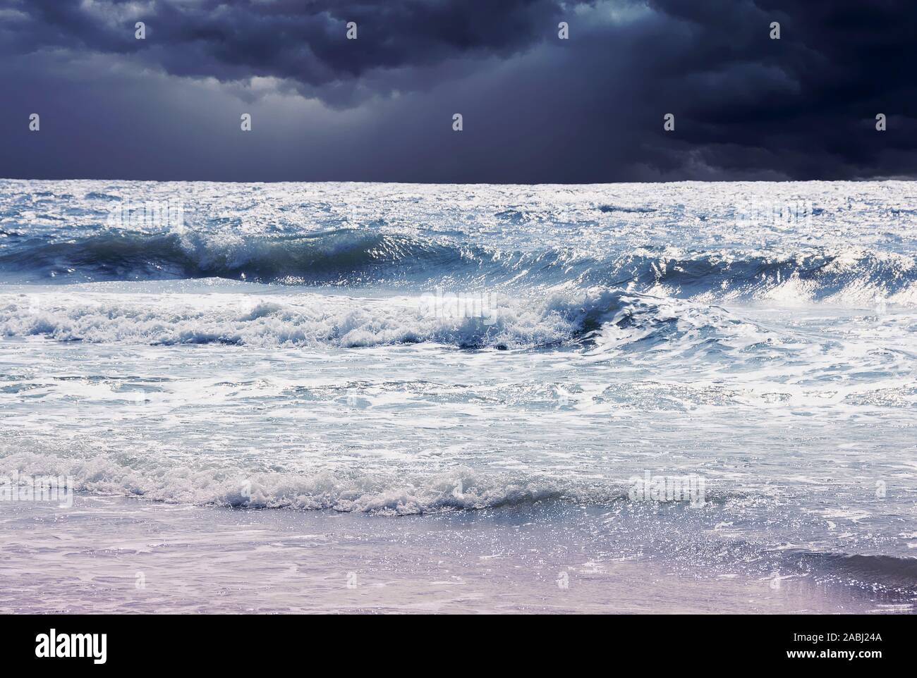 Dunkle Sturmwolken über Brandung am Strand. Stockfoto