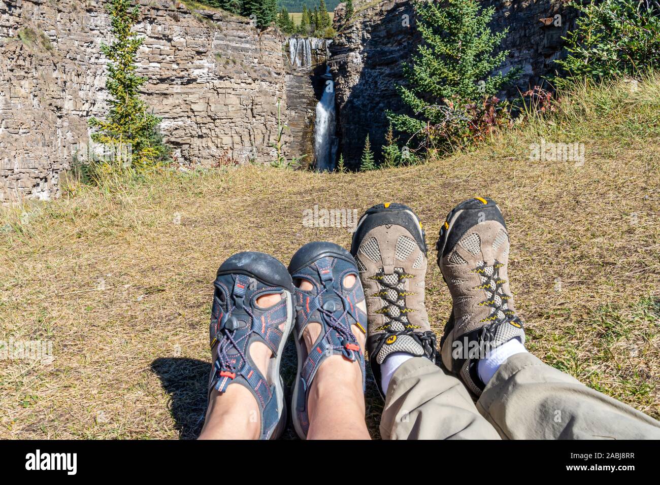 Wanderer Füße genießen den Blick auf einen wunderschönen Wasserfall. Stockfoto