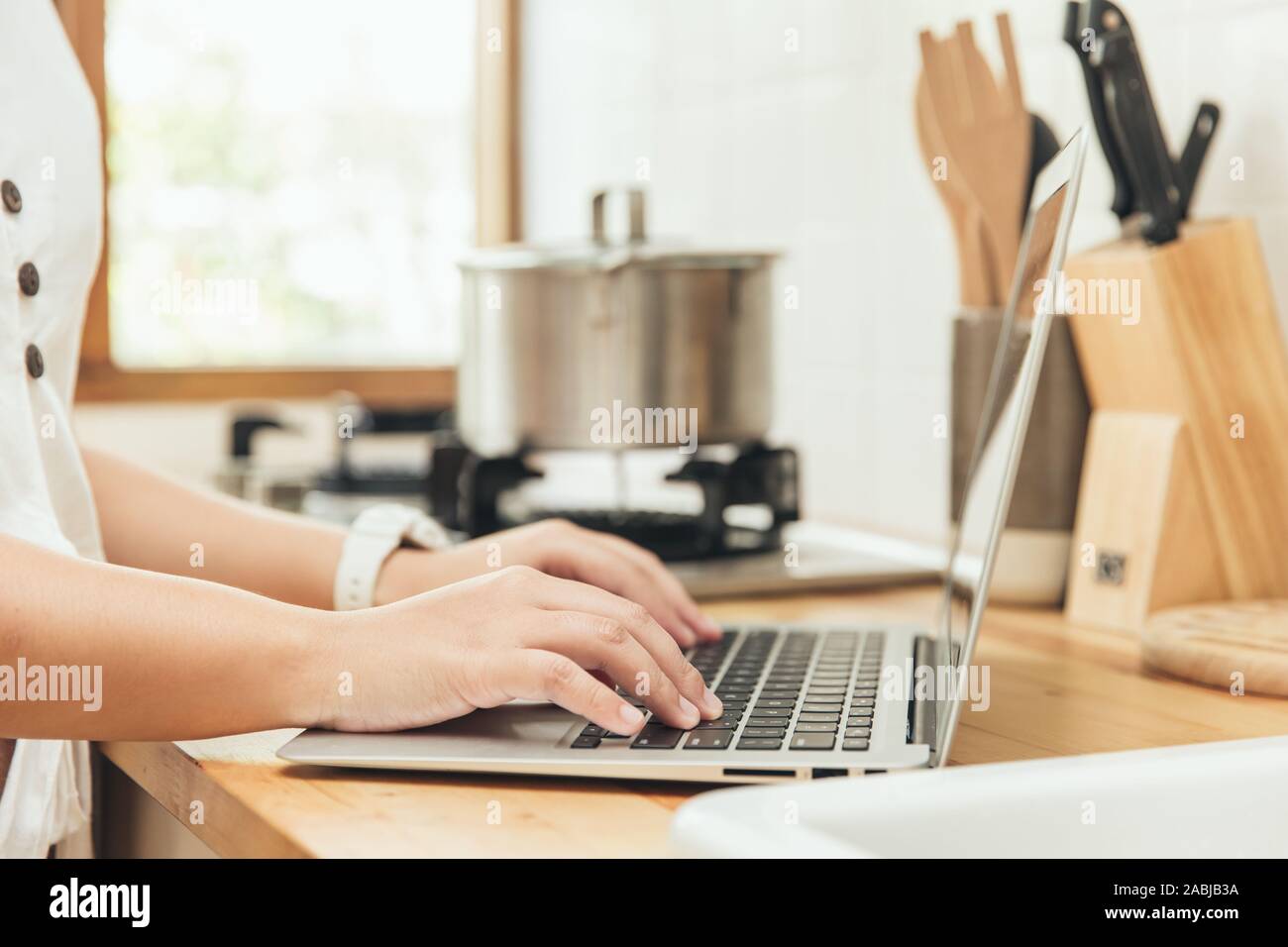 Closeup hand mit Laptop in der Küche zu lernen, Essen zu kochen oder Menü Rezept aus dem Internet finden. home Technologie Konzept. Stockfoto