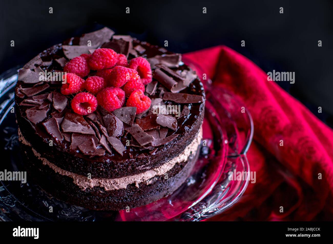 Leckere Schokolade Kuchen ist fotografiert closeup, mit Schlagsahne Schokolade, Schokolade, rasiert und mit frischen roten Himbeeren gekrönt Stockfoto