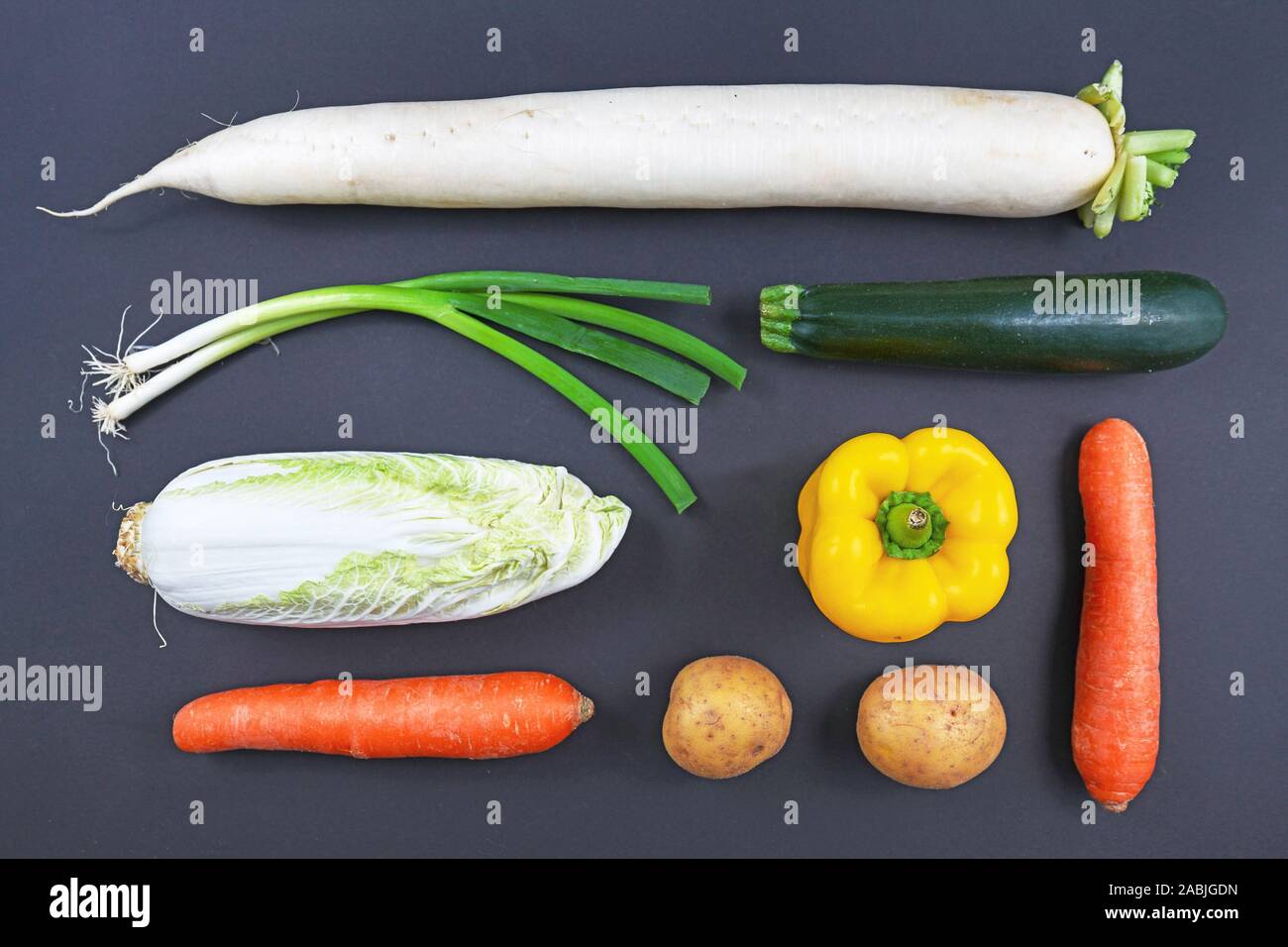 Ansicht von oben flach der verschiedenen Arten von rohem Gemüse wie Karotten, Paprika, Zucchini, Radieschen, Kartoffeln und Chinakohl auf dunklem Hintergrund Stockfoto